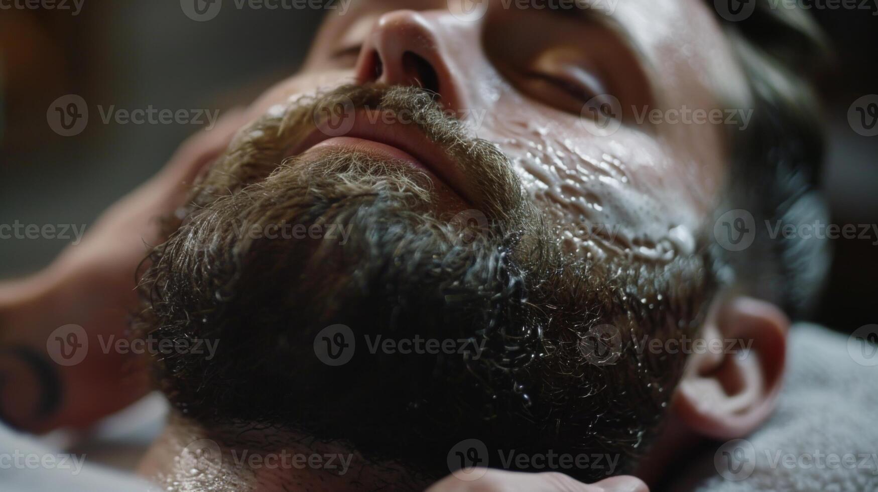 A man enjoys a soothing grooming session as a barber applies a rich beard oil to enhance his facial hair while clients chat quietly in the background. photo