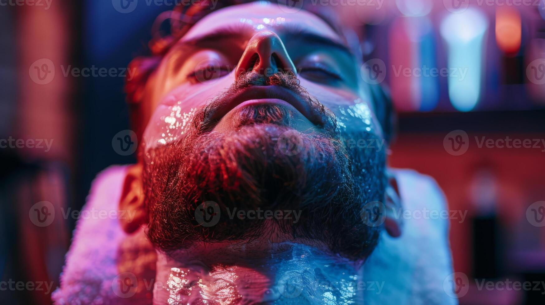 A young man lies back with a slick facial mask applied to his skin, surrounded by vibrant colored lights in a tranquil spa setting, enhancing relaxation and self care. photo