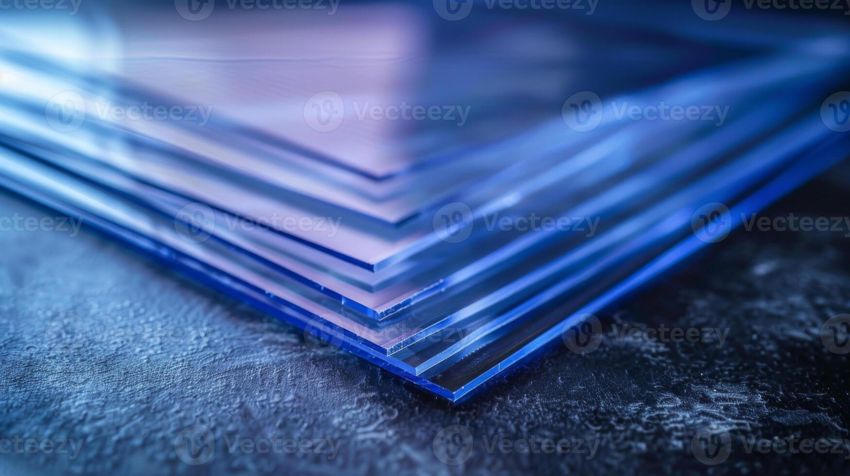 Transparent acrylic sheets are stacked in neat layers on a dark, textured surface, showcasing their clarity and modern design in a well lit space. photo