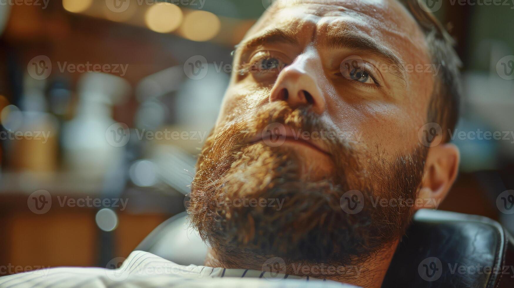 A man lies back in a barbershop chair, receiving a beard grooming treatment. The ambiance is warm and inviting, with tools and products visible in the background. photo