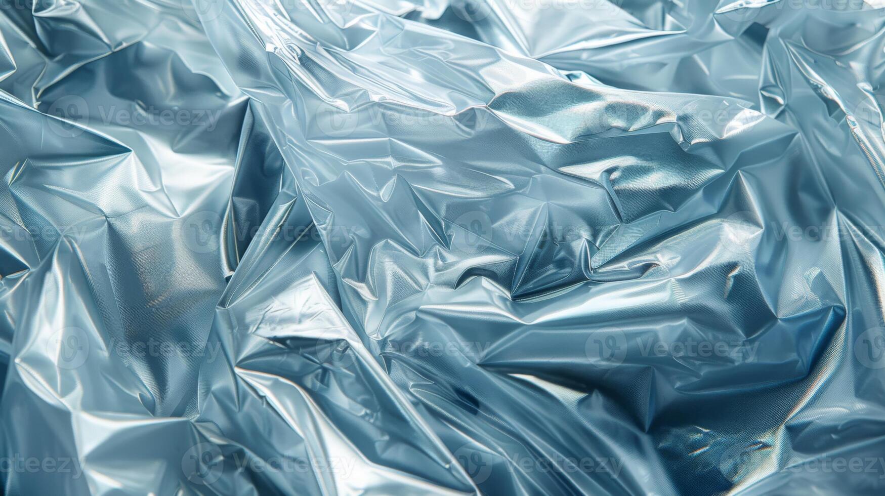 Blue plastic sheets are crumpled together, displaying a glossy surface with fascinating light reflections. The texture highlights the interplay of shadows and creases, creating depth. photo