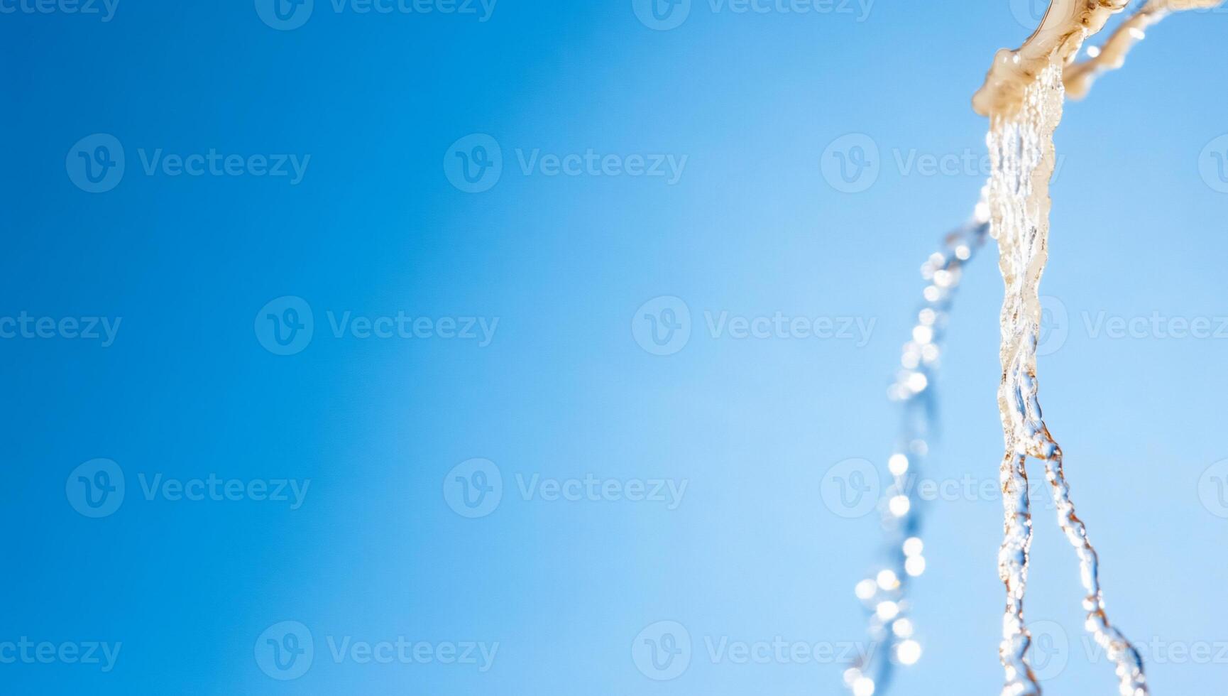 Water flowing against a clear blue sky, creating a refreshing scene. photo