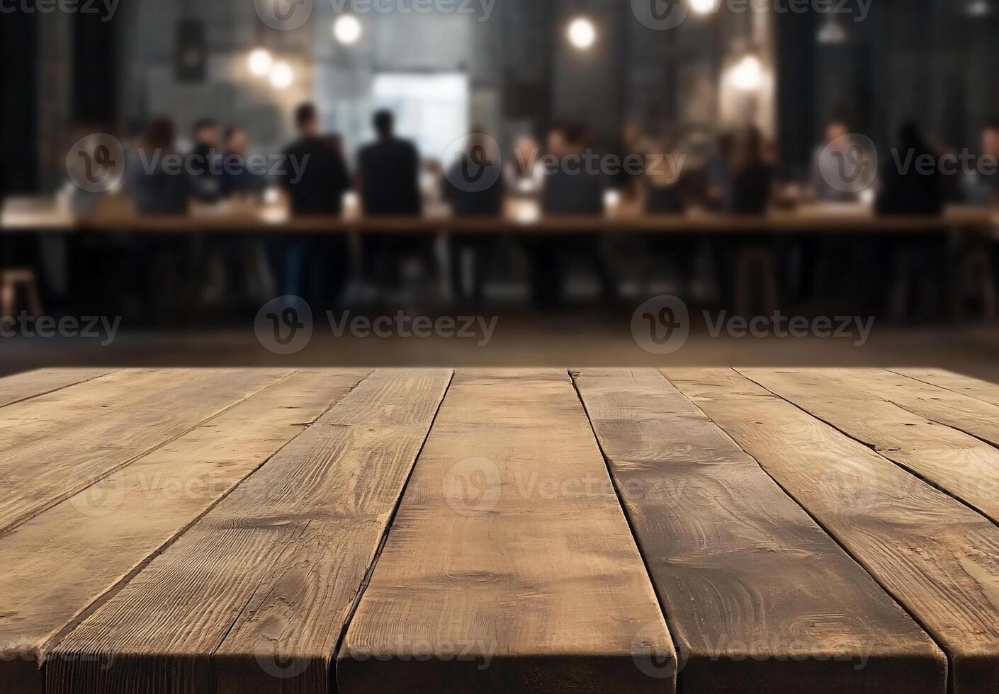 A wooden table in the foreground with people dining in the background. photo