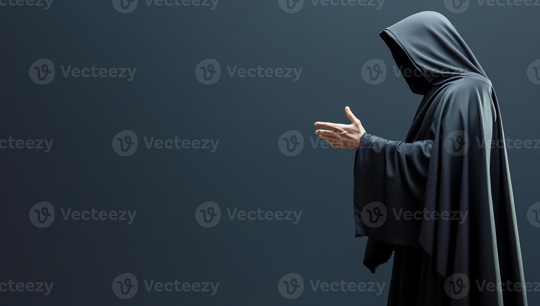 A cloaked figure gesturing in a dark, minimalist setting. photo