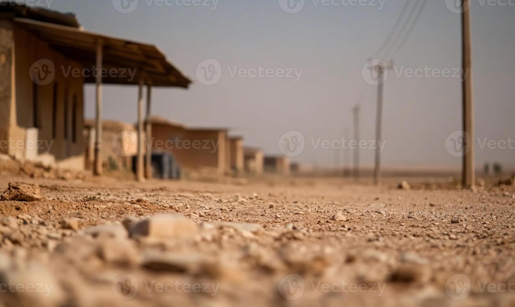 A dusty road lined with simple structures in a barren landscape. photo