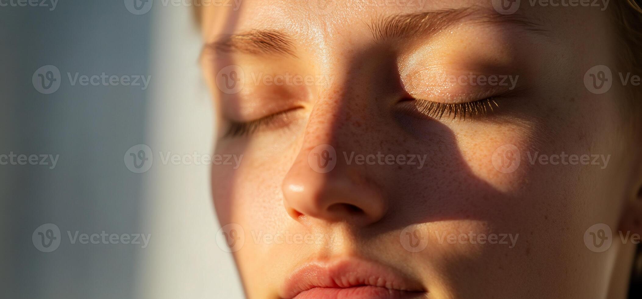 Close-up of a serene face with closed eyes, illuminated by sunlight. photo