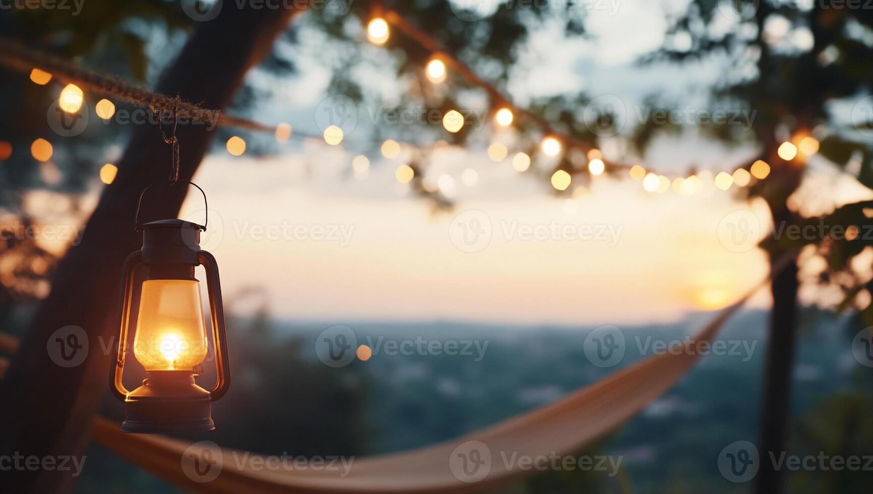 A cozy outdoor scene with a lantern and string lights at sunset. photo