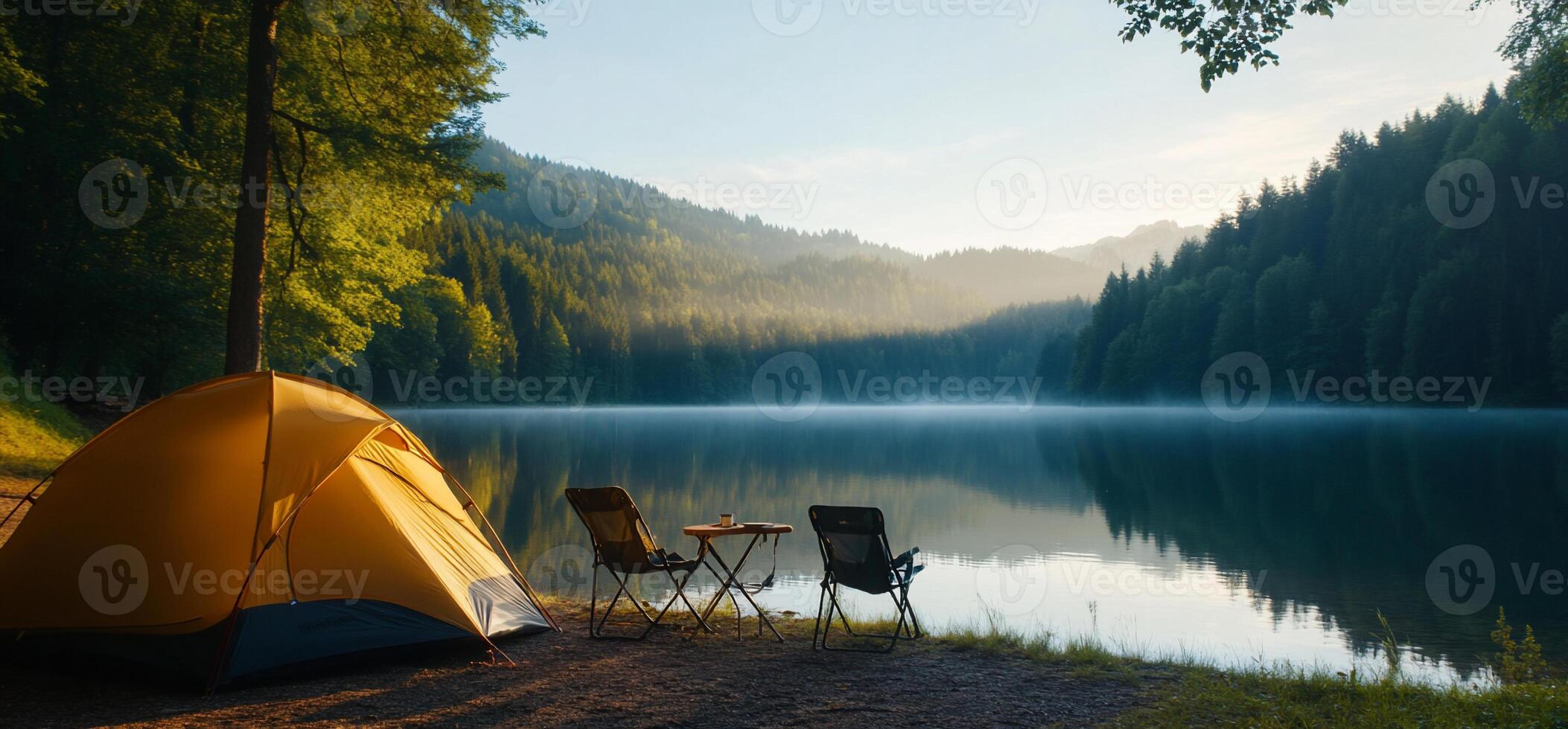 Serene lakeside camping scene at dawn with a tent and chairs. photo