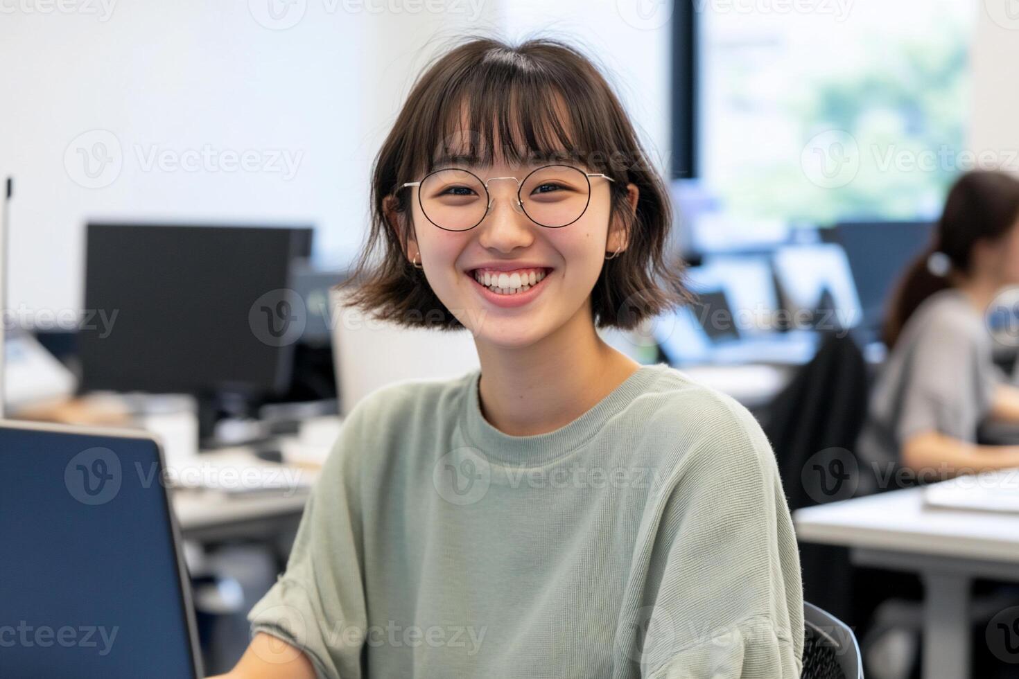 A smiling young woman in an office setting, engaging with her work. photo