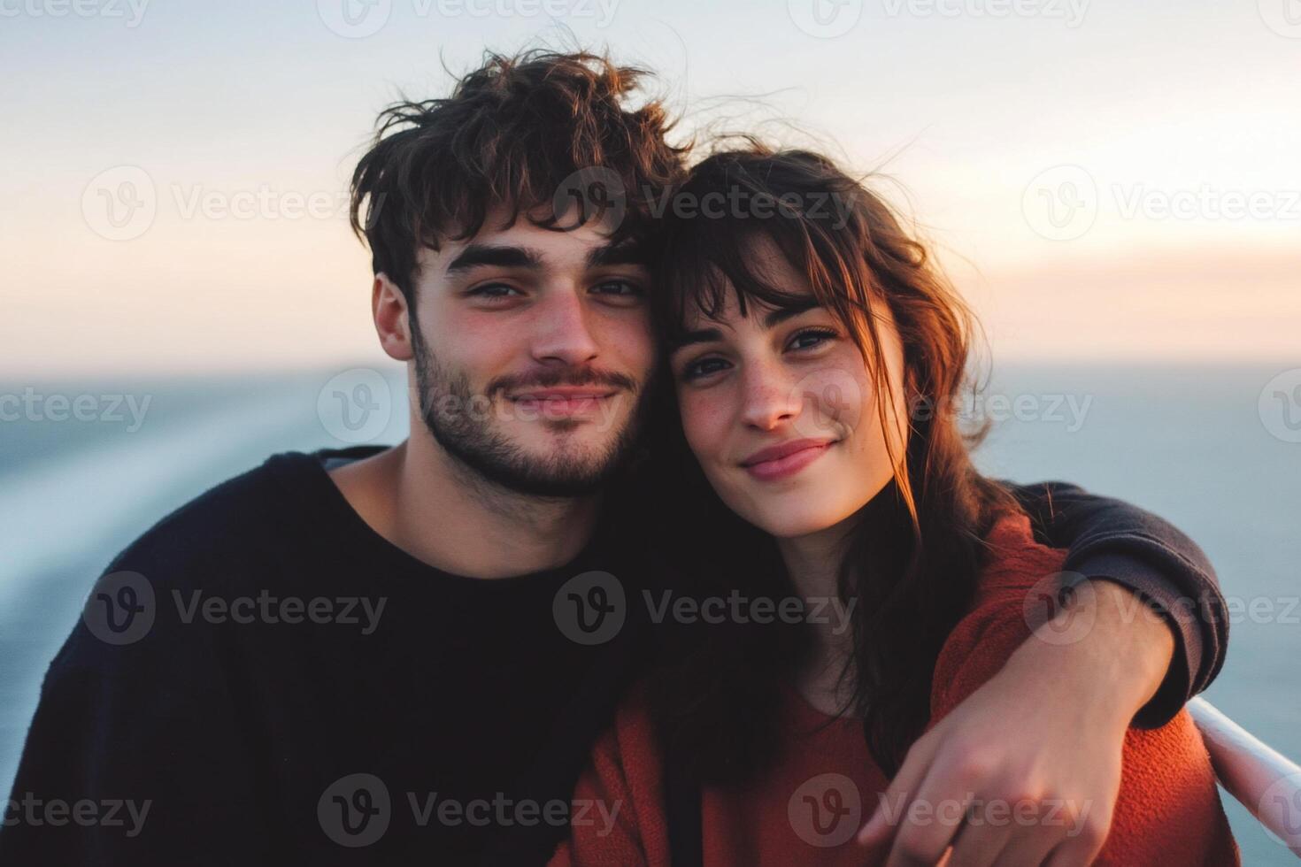 A couple smiling together against a scenic ocean backdrop. photo
