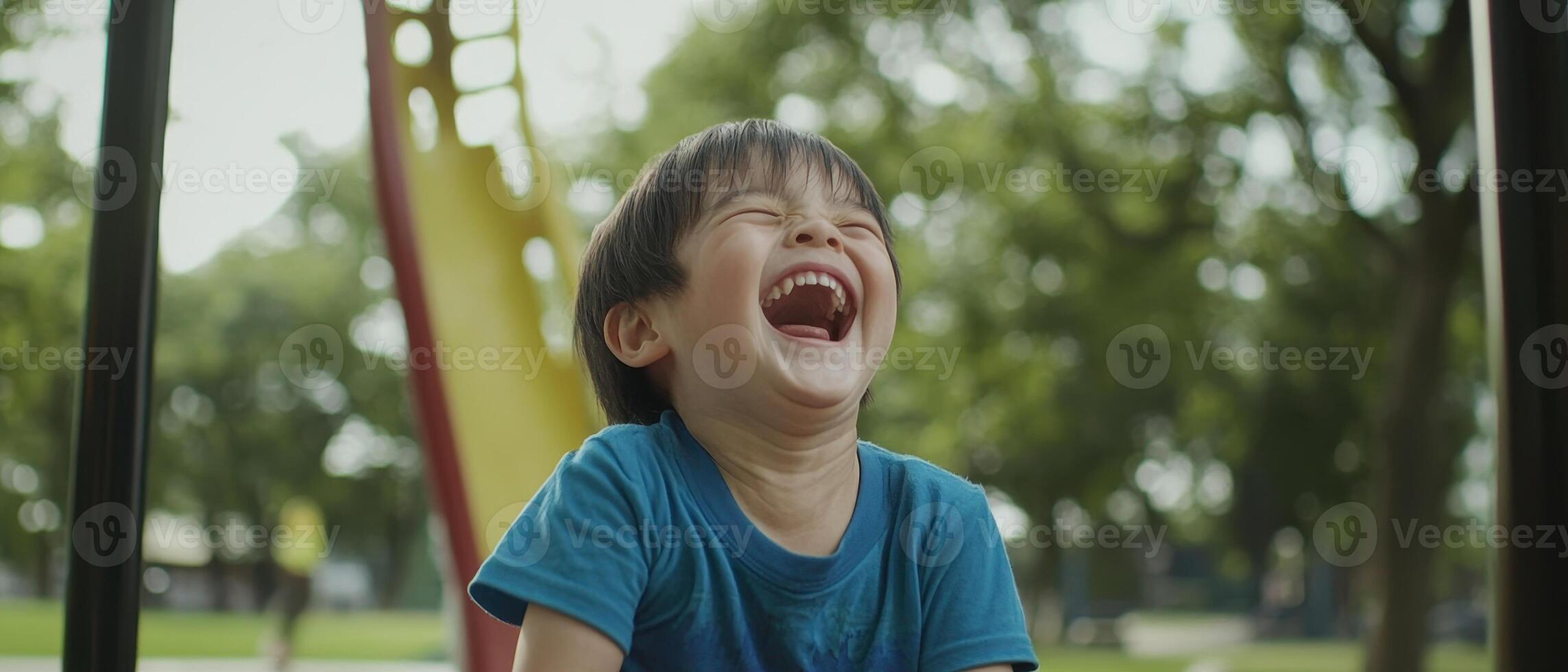 A joyful child laughs on a playground, surrounded by greenery, capturing the essence of happiness and innocence. photo
