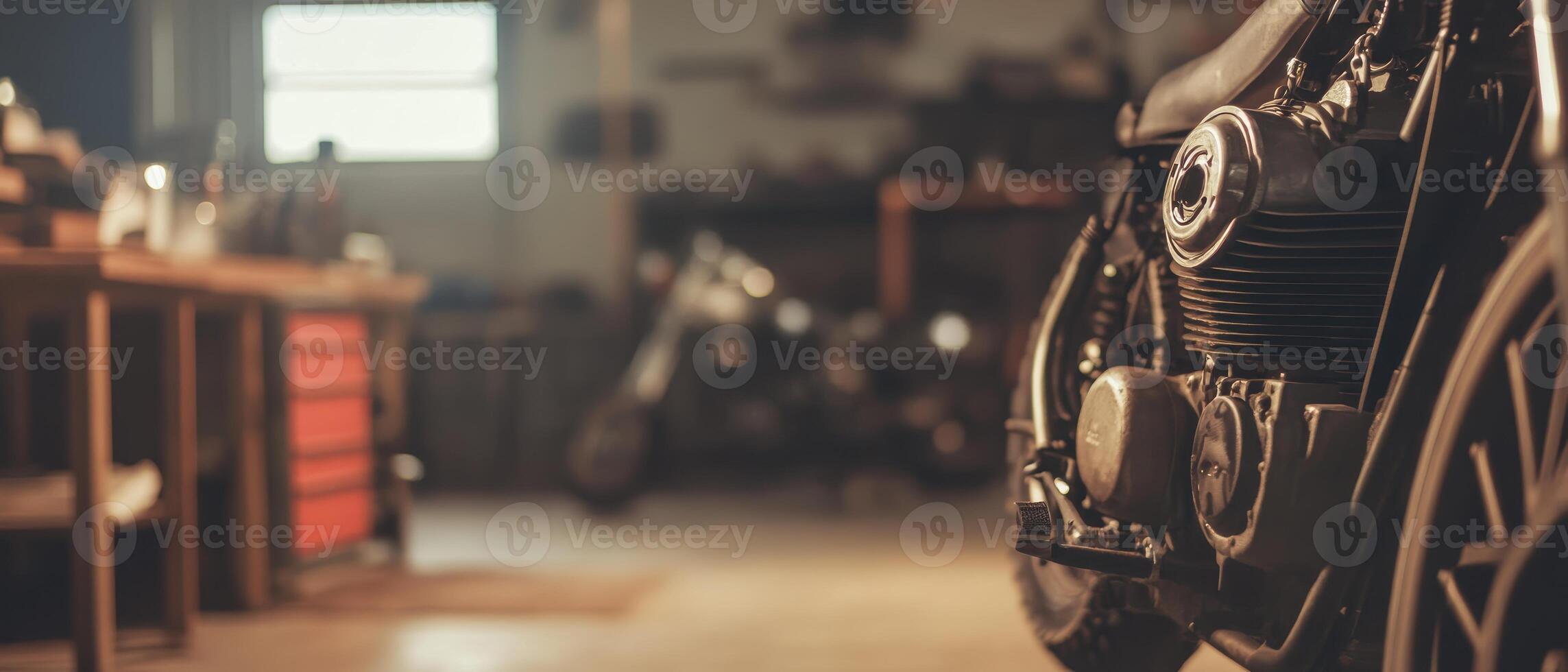 A close-up view of a motorcycle in a workshop, showcasing the engine and tools, with another bike blurred in the background. photo