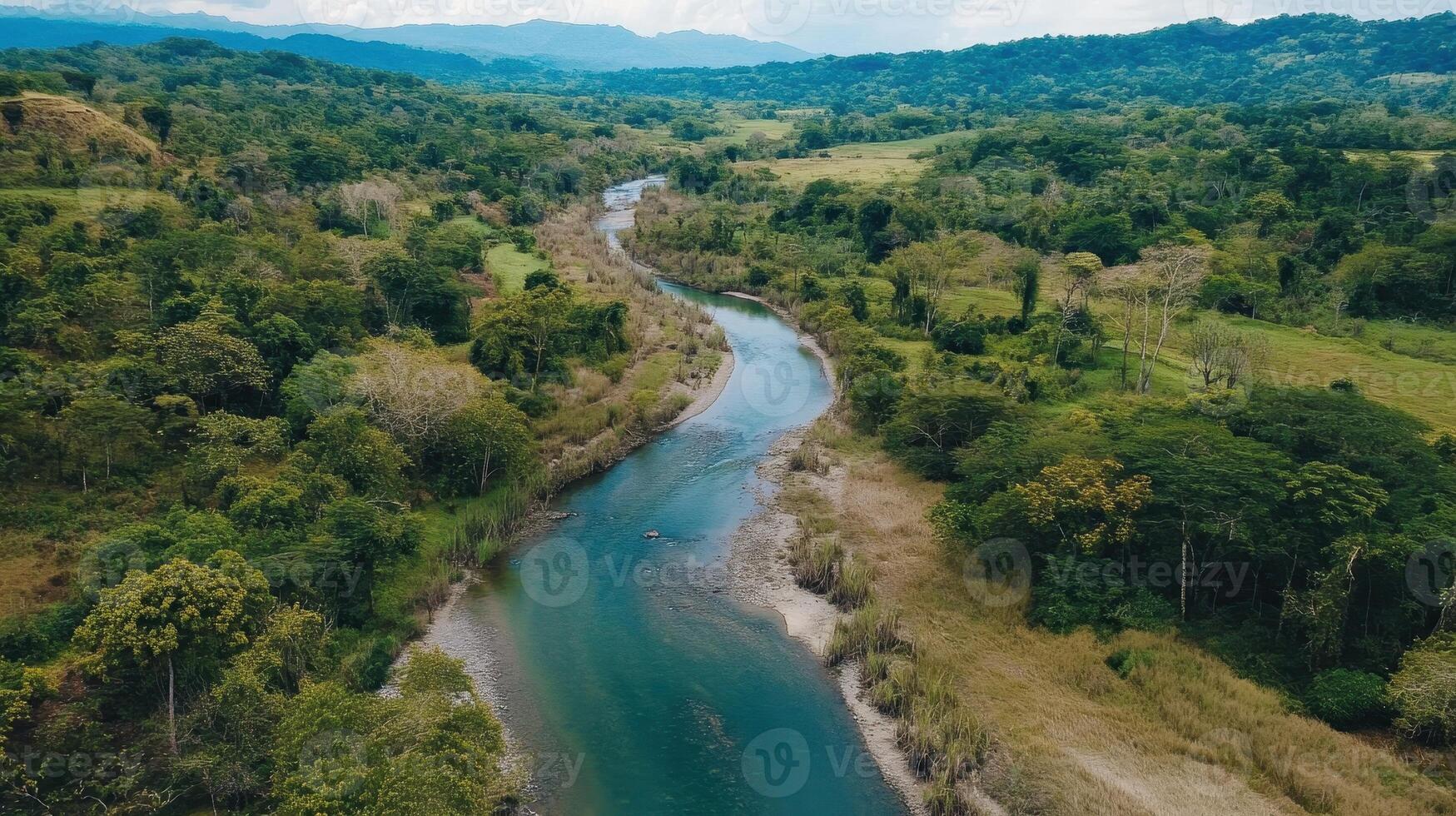 A serene river winds through lush greenery, surrounded by rolling hills and a tranquil landscape, capturing the beauty of nature. photo