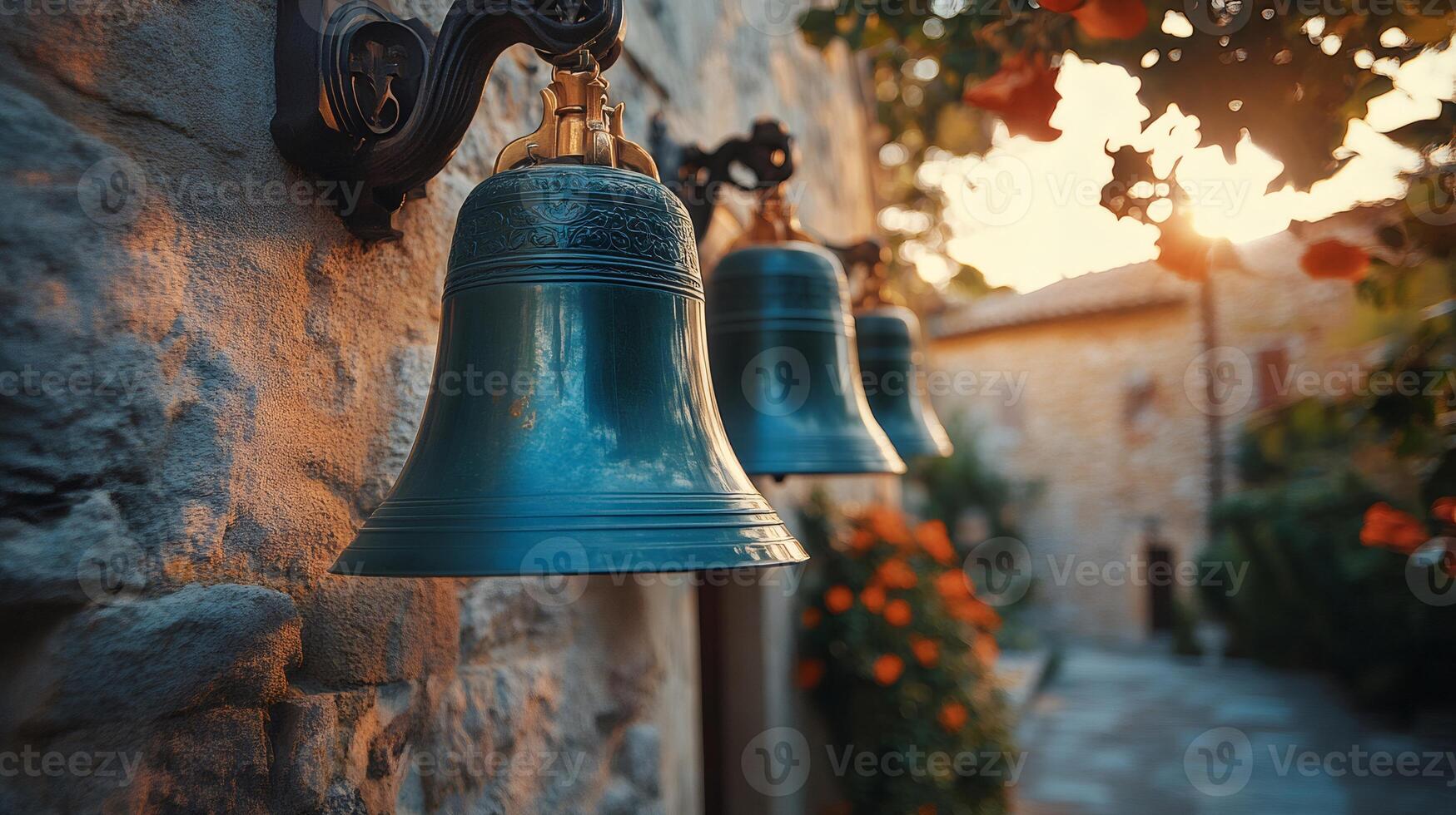 Church bells hanging on a stone wall at sunset photo