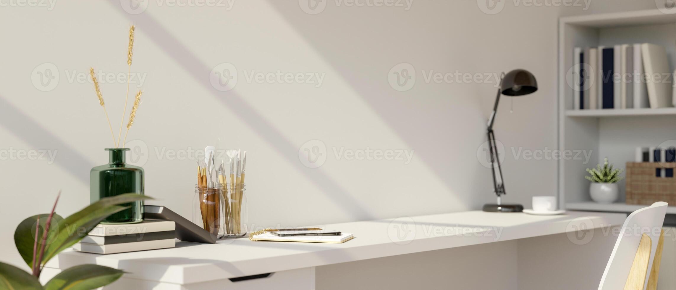 A white desk with painting tools, books, and decorative items, set in a minimalist white room. photo