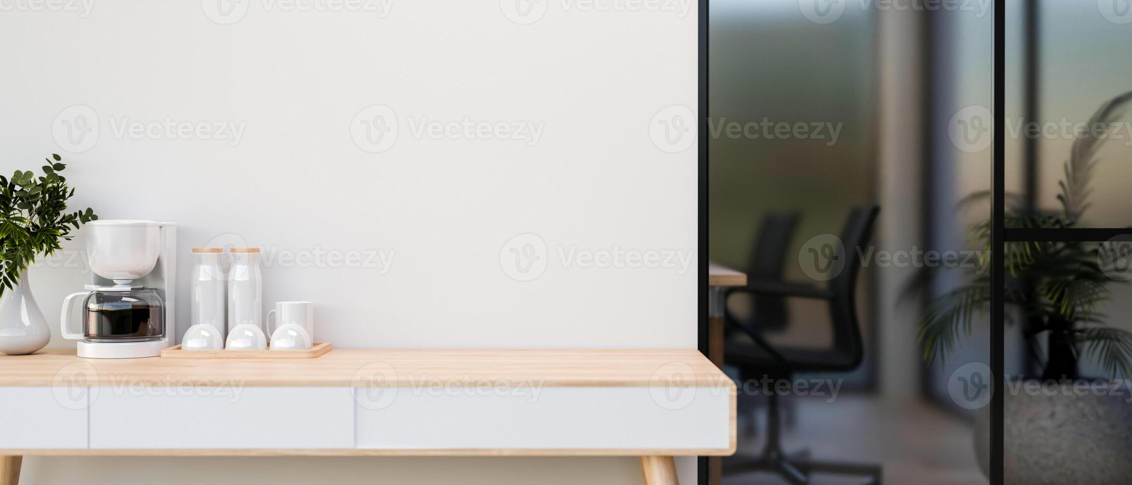 A coffee maker on the wooden table beside the white wall of company meeting room. photo