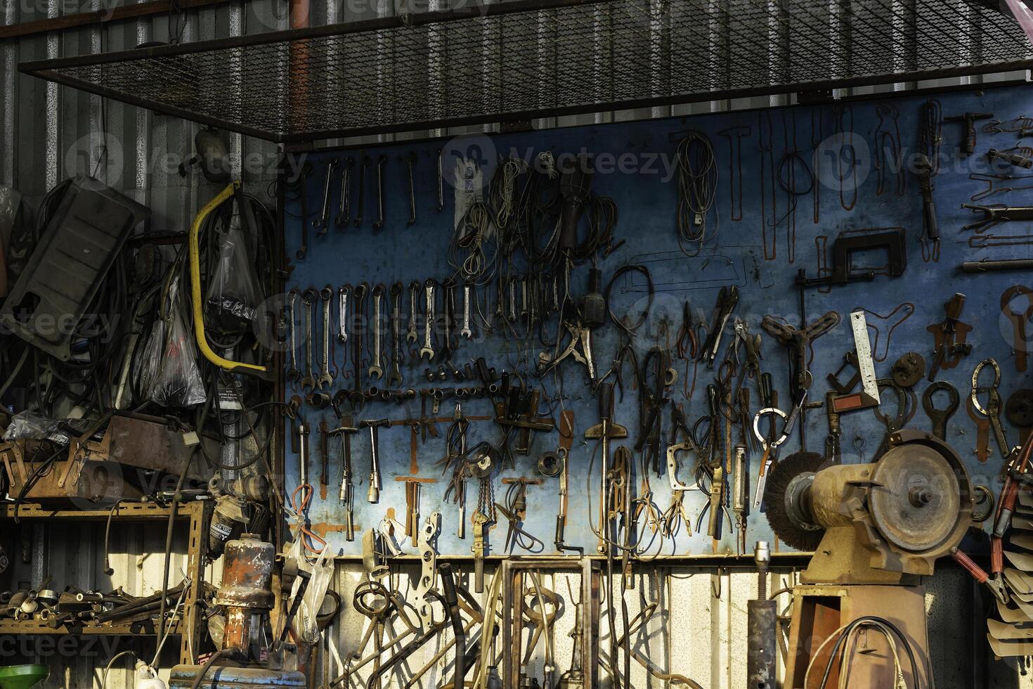 A tool hanging board with various equipment, looks old and has been used for a long time. photo