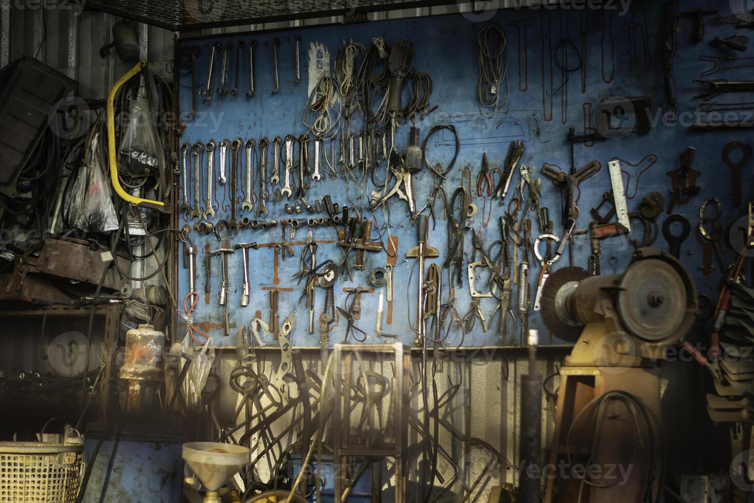 A tool hanging board with various equipment. It looks old and has been used for a long time. It has some rust. photo