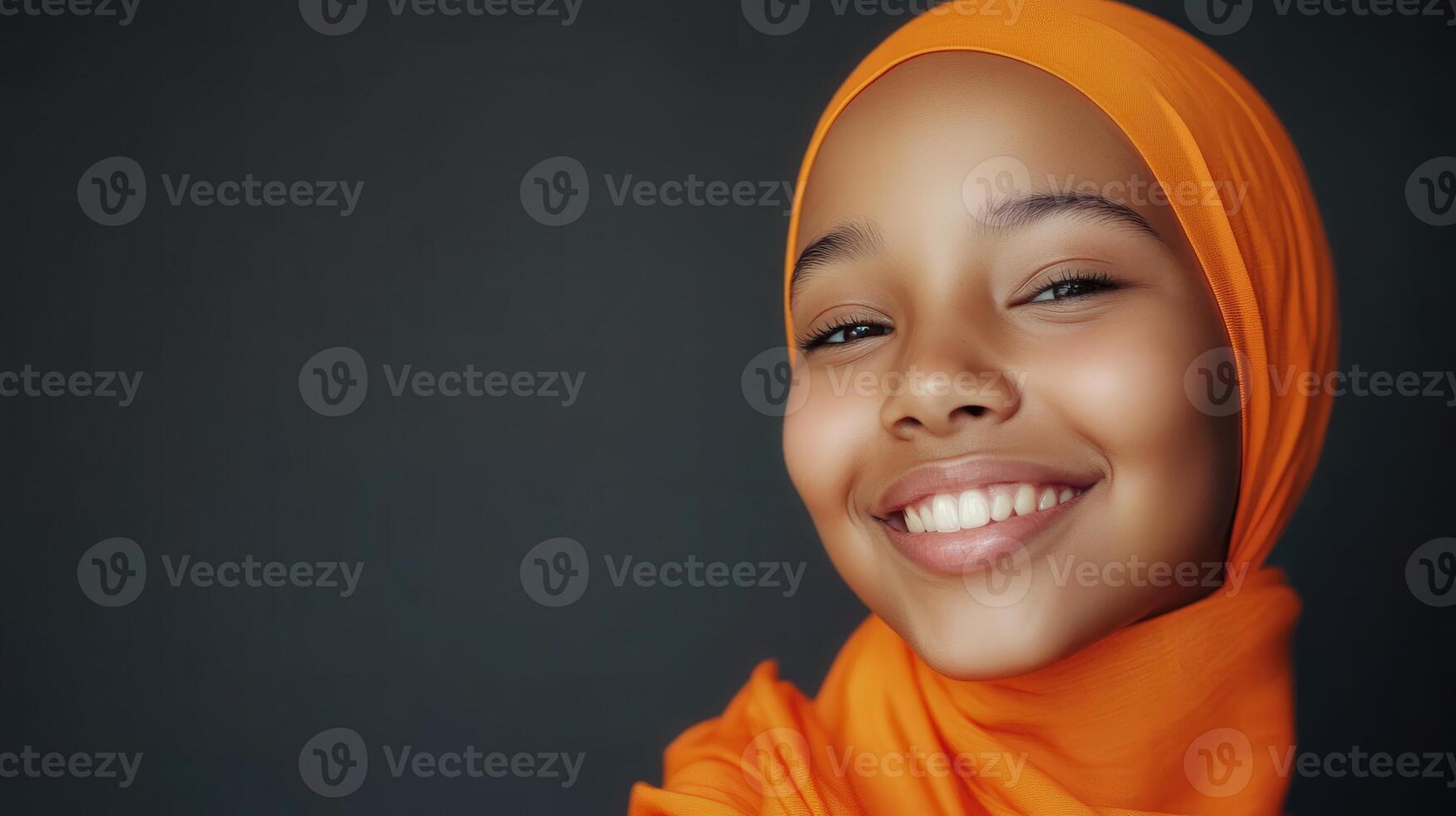 A Young Girl Smiles Wearing An Orange Headscarf photo