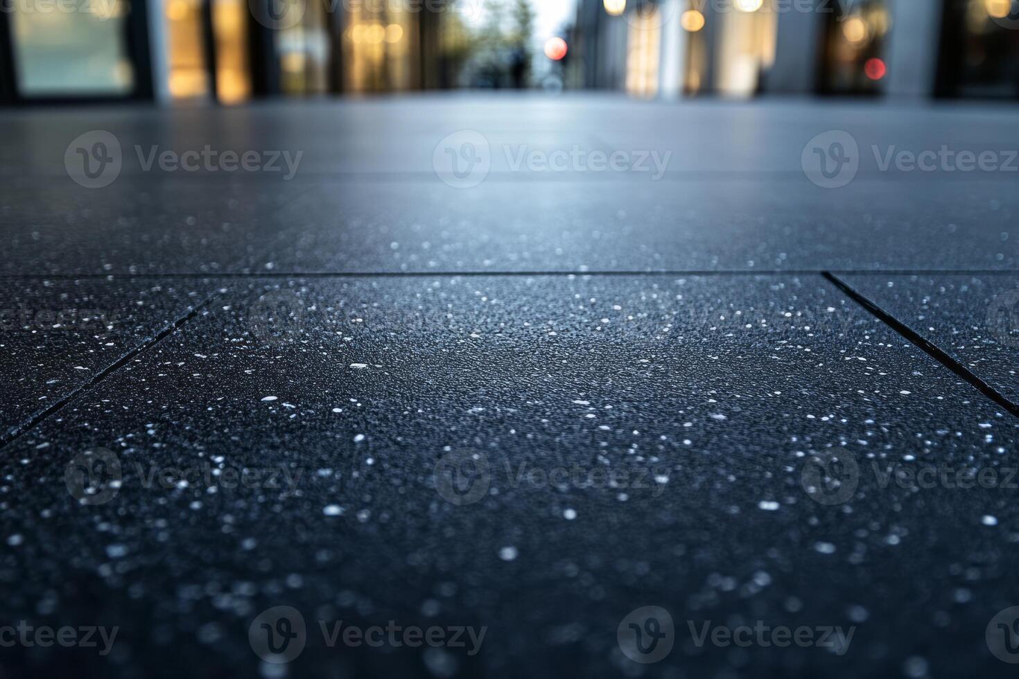 A close-up view of wet, textured pavement reflecting soft ambient light in an urban setting. photo