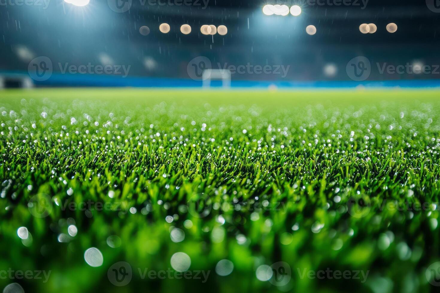 Close-up of vibrant green artificial turf in a rain-soaked stadium, highlighting droplets of water reflecting bright stadium lights. photo