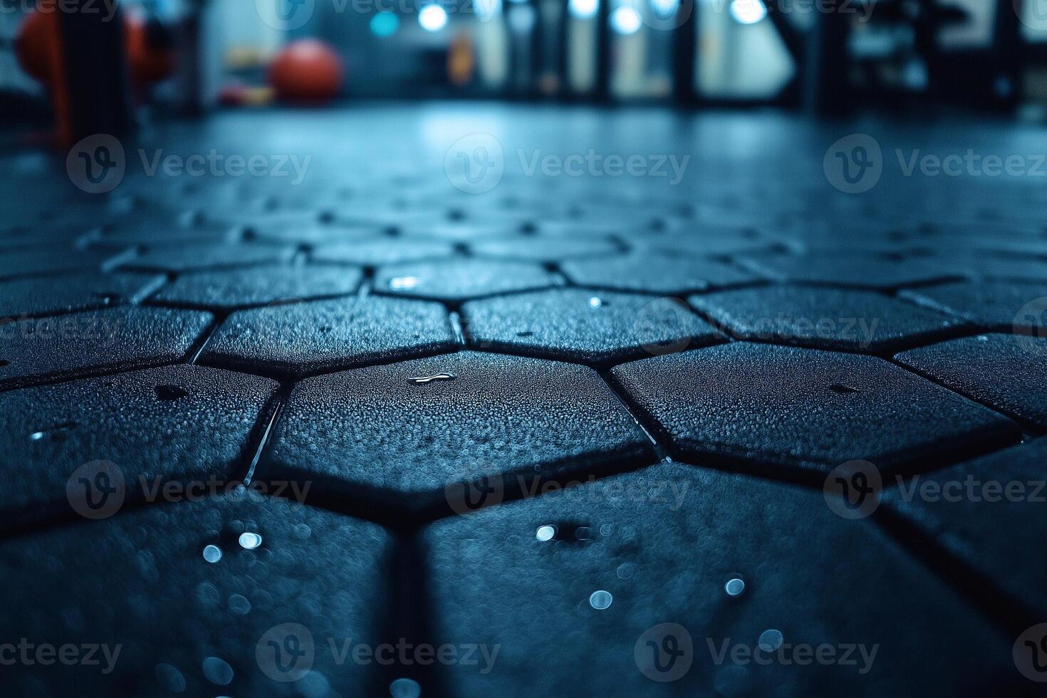 Close-up of a textured gym floor with hexagonal tiles, showcasing droplets of moisture and vibrant ambient lighting. photo