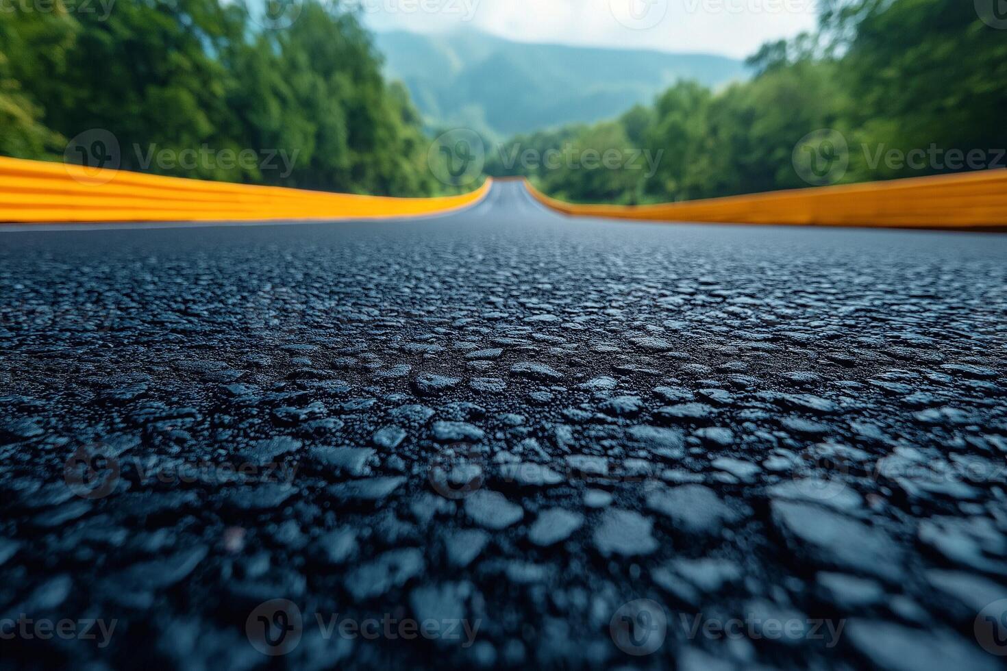 A low-angle view of a winding asphalt road surrounded by lush greenery, creating a serene and adventurous atmosphere. photo