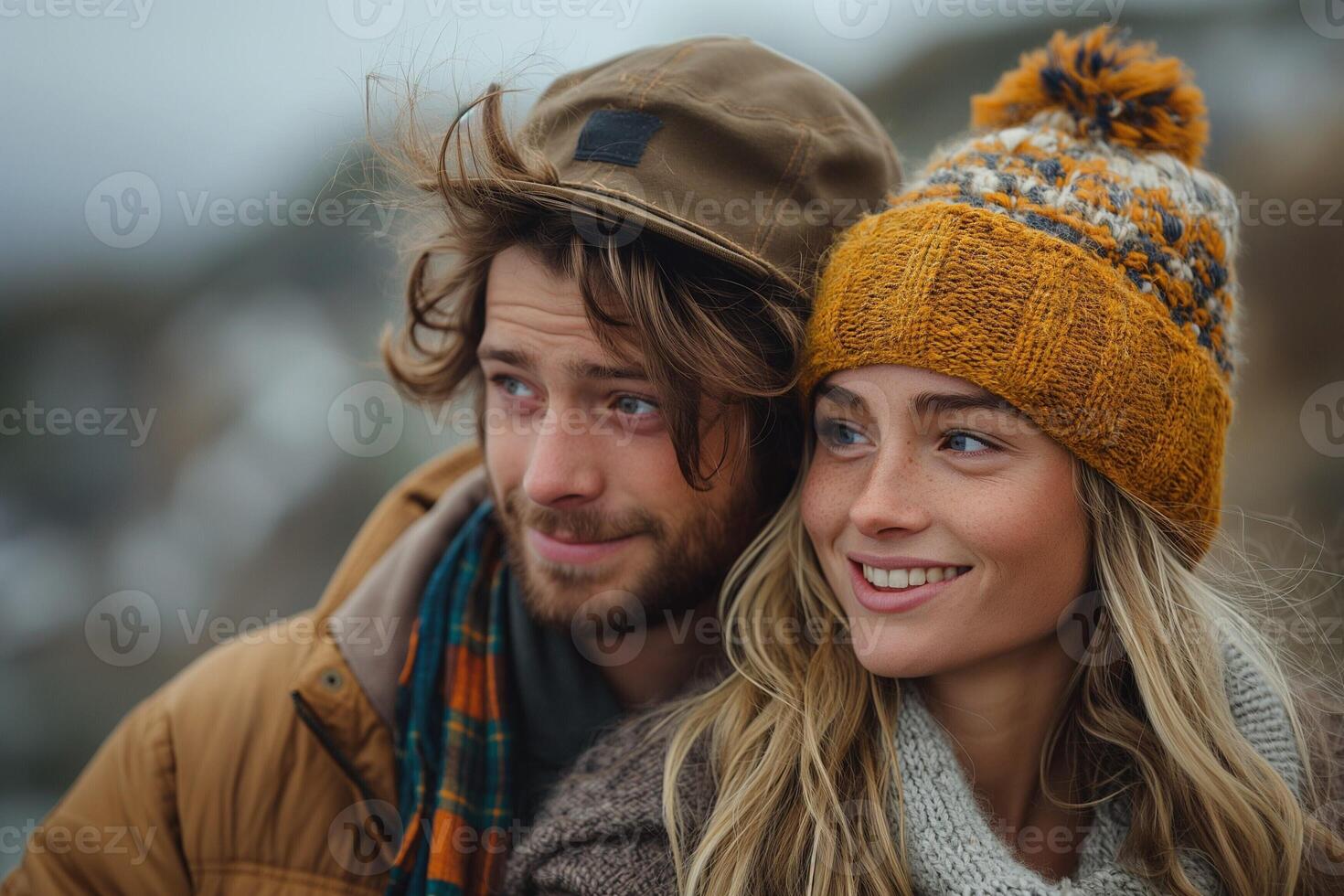 A young couple, a man and a woman, smiling warmly while enjoying a chilly outdoor moment on a windy day. photo