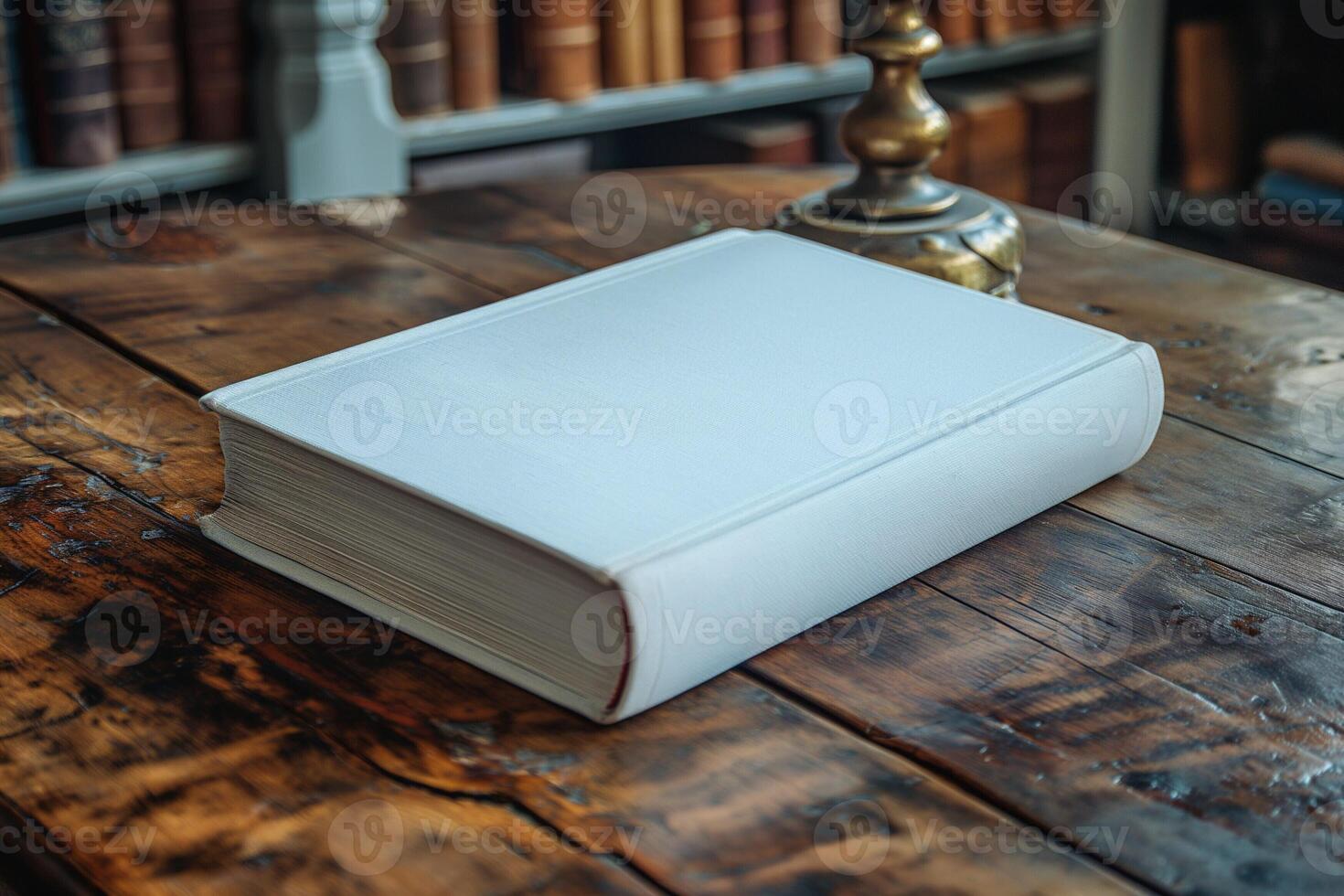 A pristine white book resting on a rustic wooden table in a cozy library setting. photo