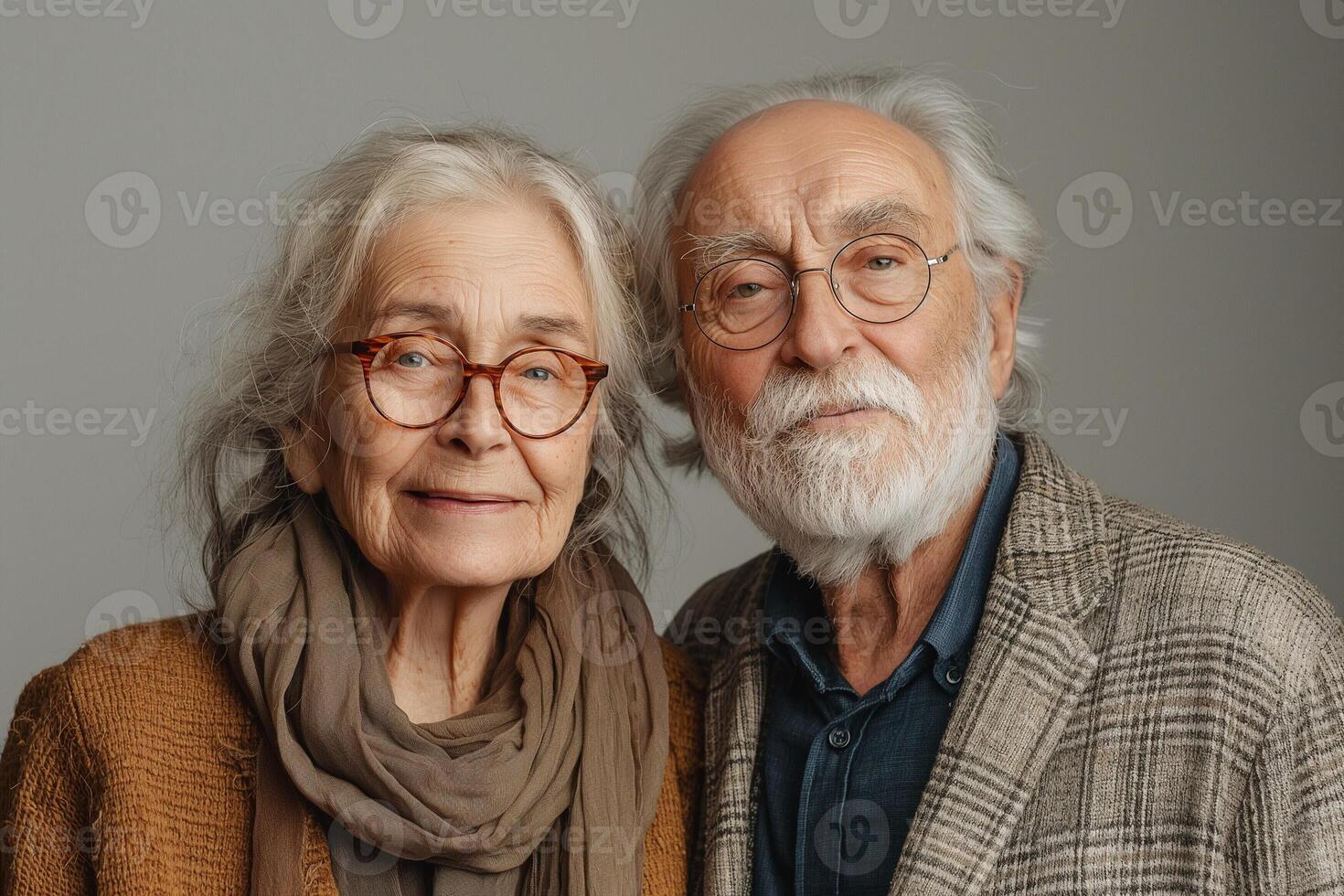Elderly couple with grey hair, smiling warmly at the camera against a neutral backdrop, showcasing their loving relationship. photo