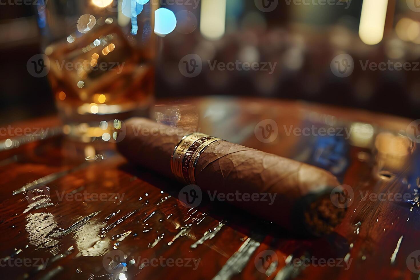 A cigar sitting on a wooden table with a glass of whiskey photo