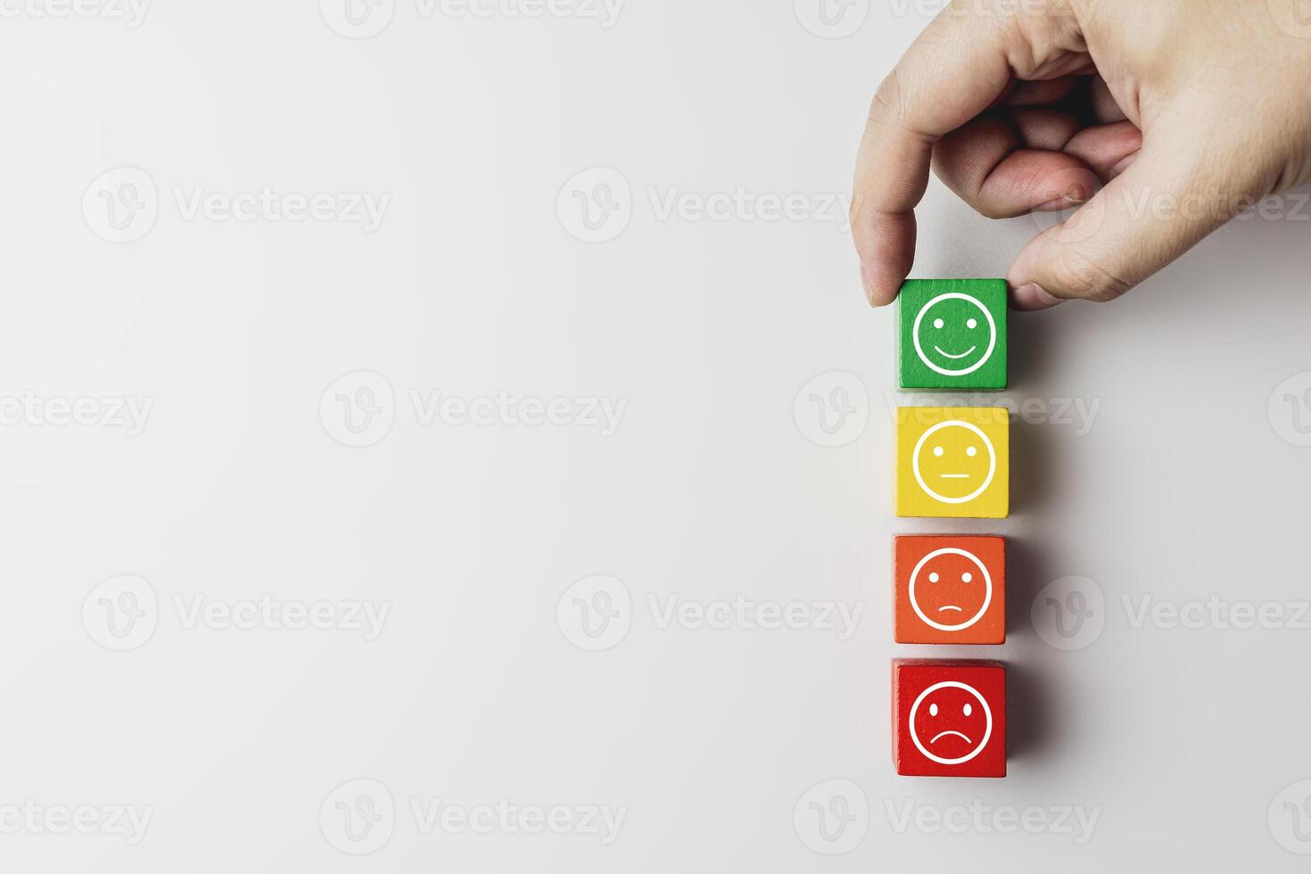 Hand placing green wooden blocks with emoticon faces feel happy according to color scale. Concept of satisfaction rating, customer evaluation, and satisfaction survey. with copy space photo