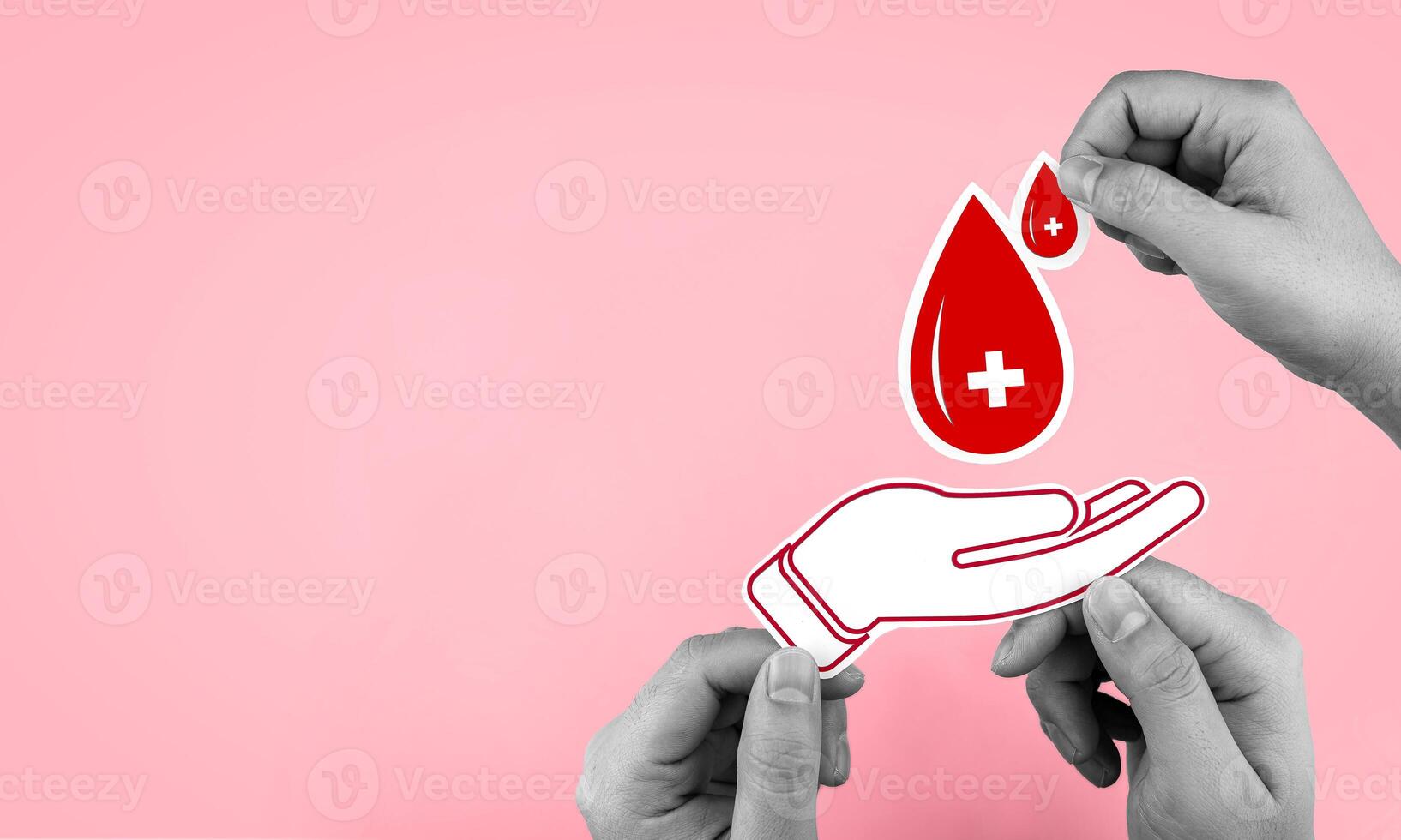 Top view of male hand holding a drop of blood with paper hands on pink background. With copy space. Concept of blood donation, health benefits for donors, blood banks, and World Blood Donor Day. photo