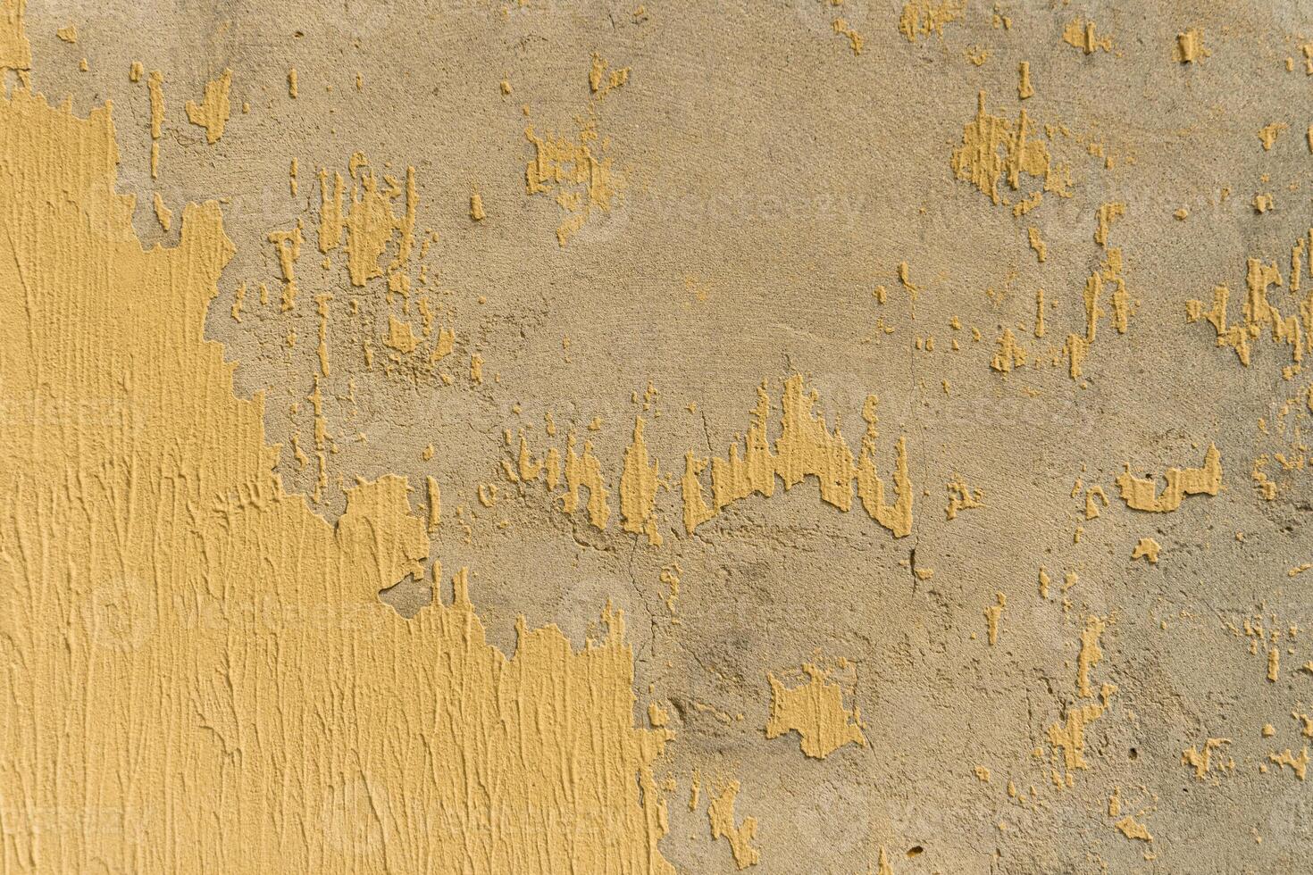 A yellow painted wall with peeling paint photo