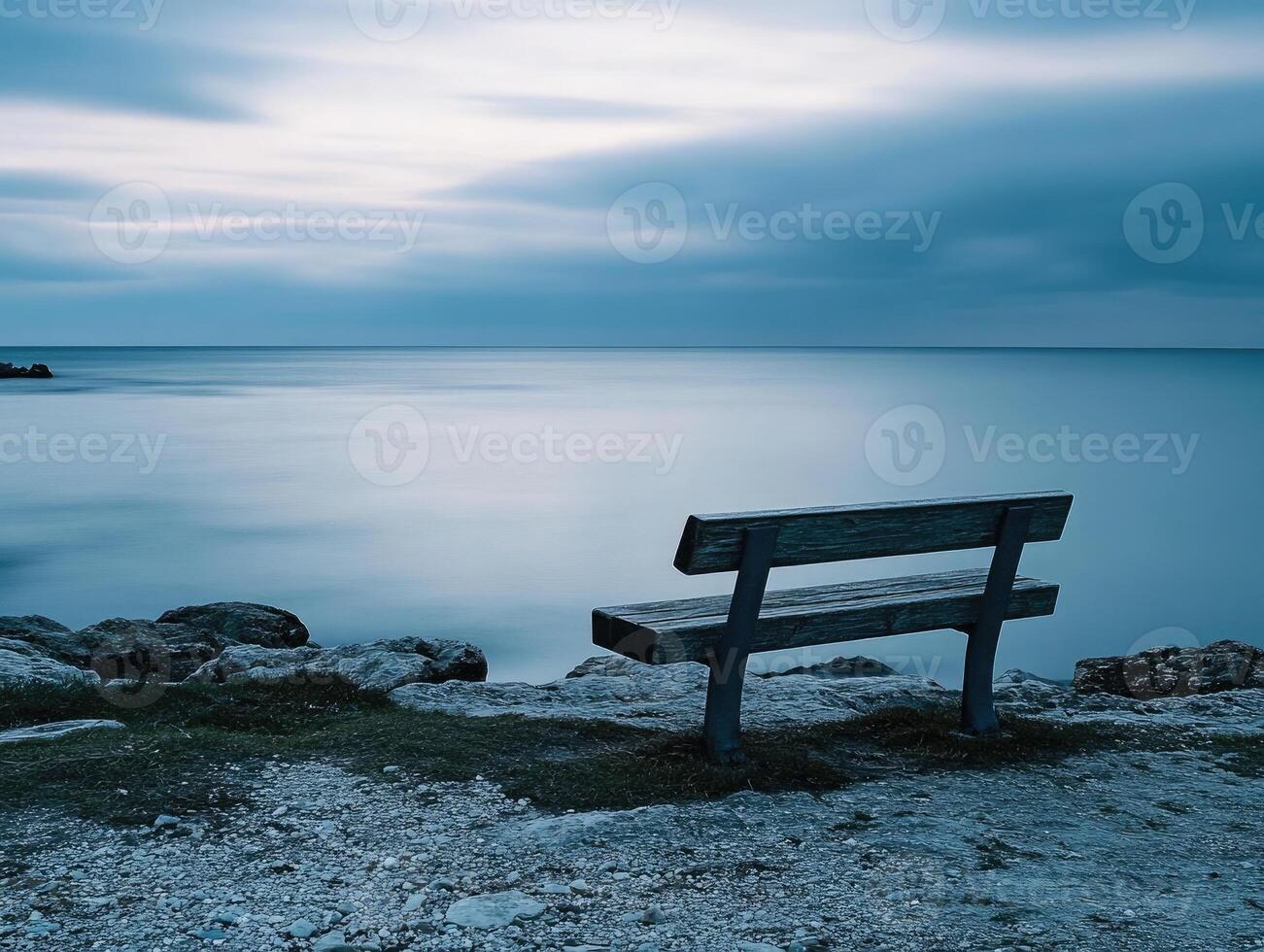 Serene coastal bench overlooking calm waters at twilight with gentle waves photo