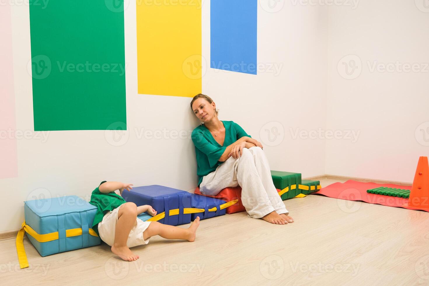 A woman and child sitting on colorful blocks in a room photo
