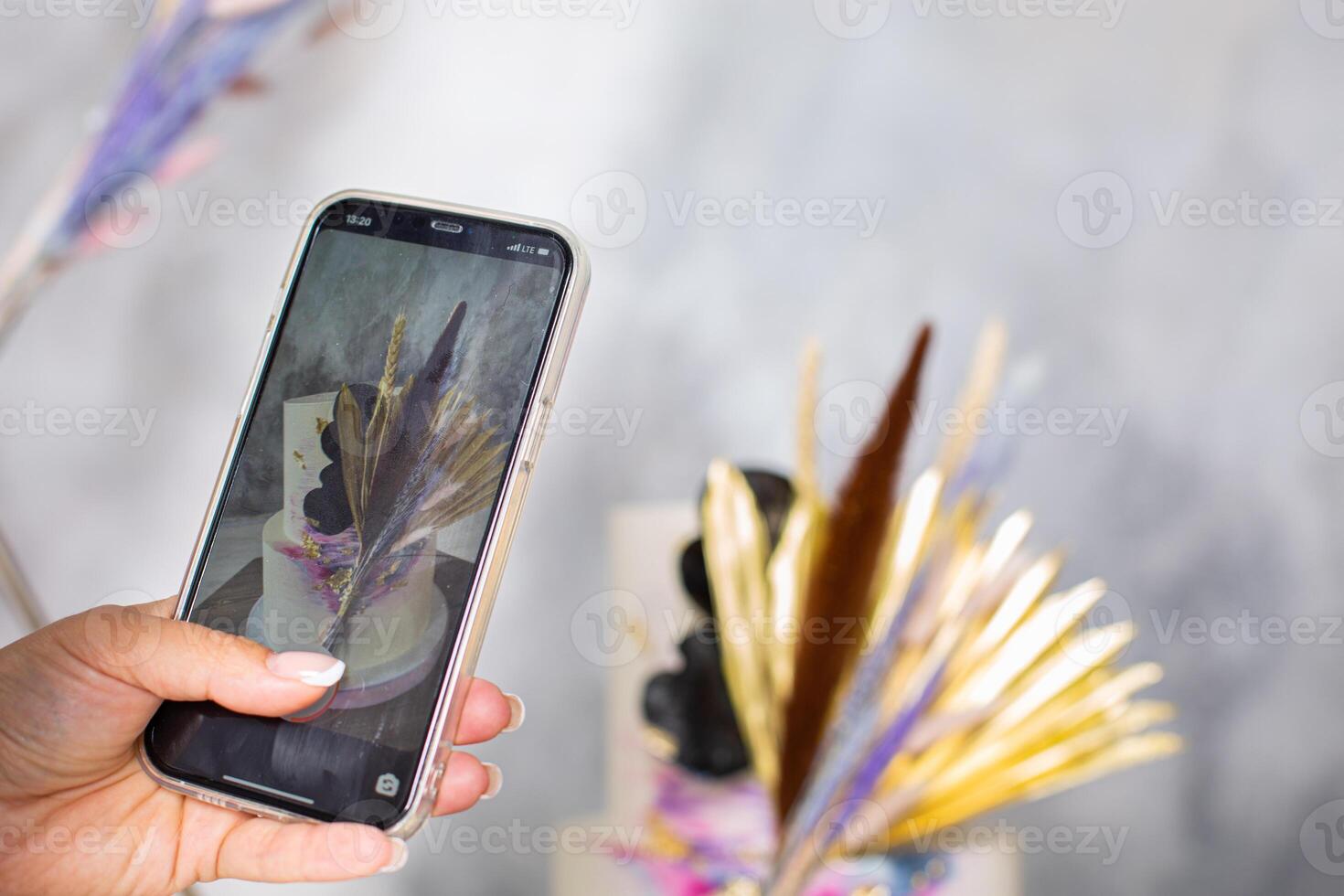A person holding up a cell phone with a photo of a cake