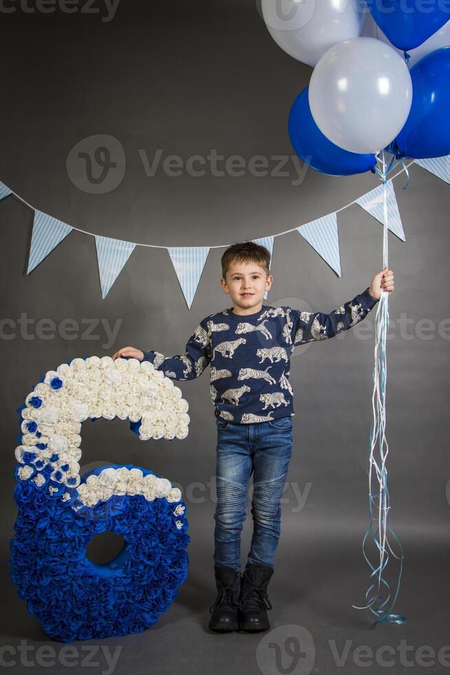 A young boy standing next to a large blue and white number six photo