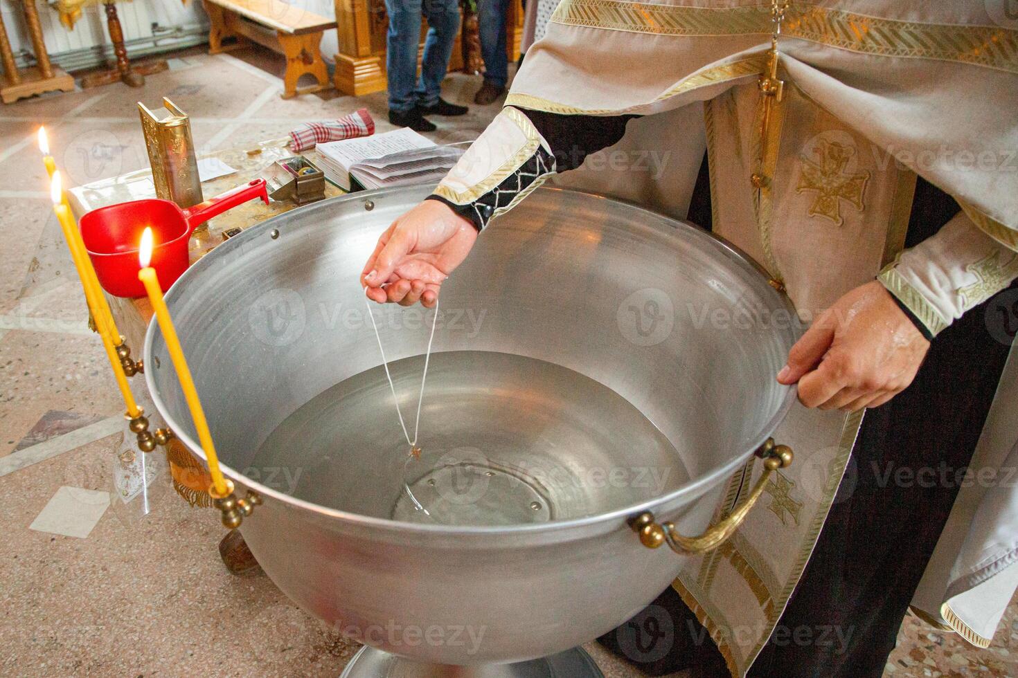 A priest is pouring water into a metal bowl photo