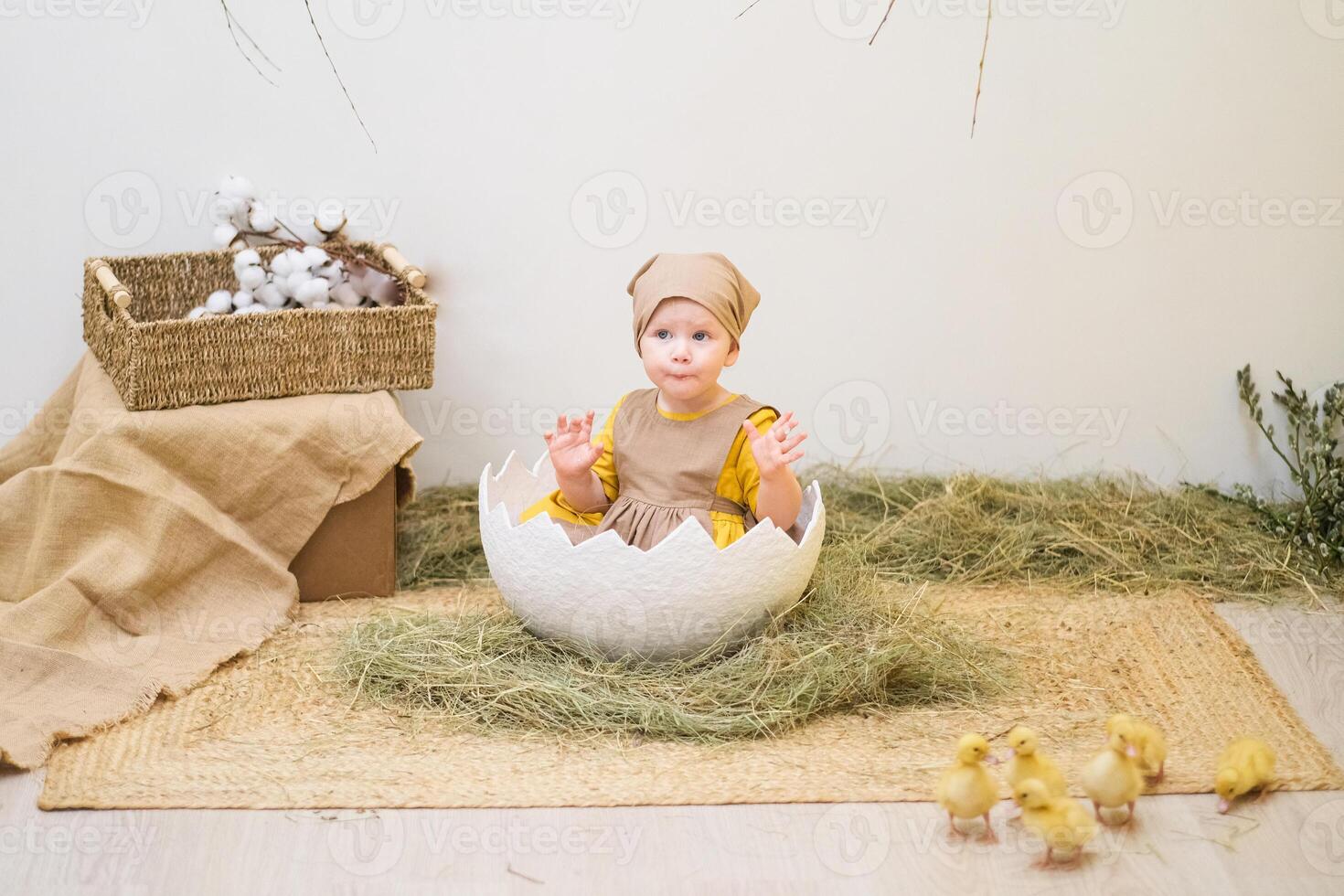 A baby in a hat sitting in a white egg photo