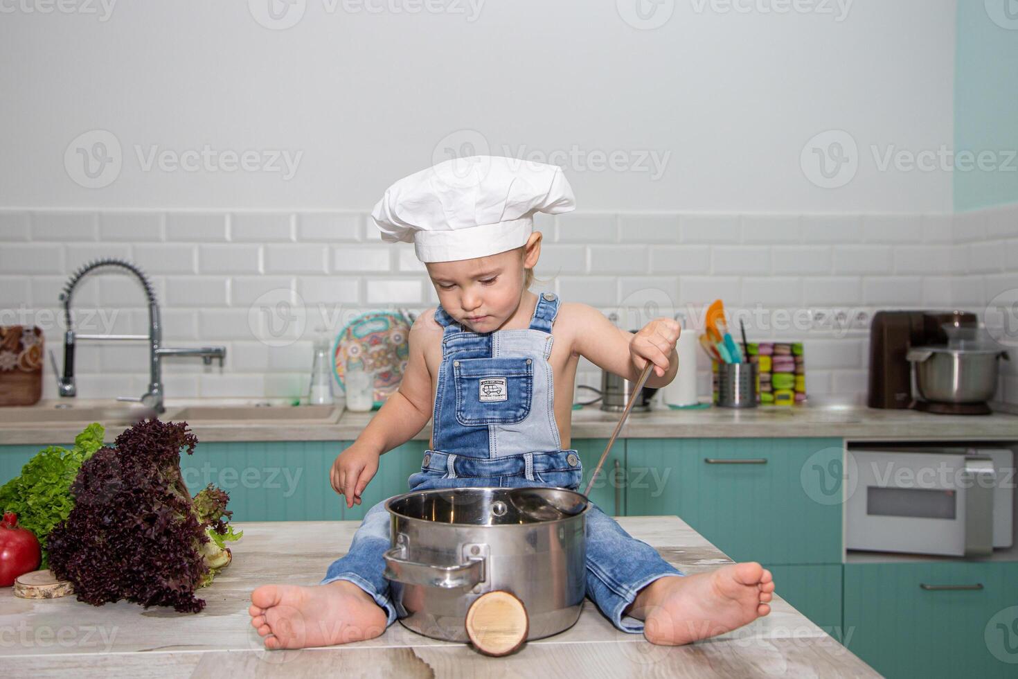 A little boy in overalls and a chef hat cooking on a counter photo