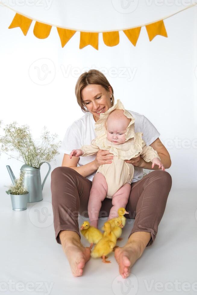 A woman holding a baby and holding a duckling photo