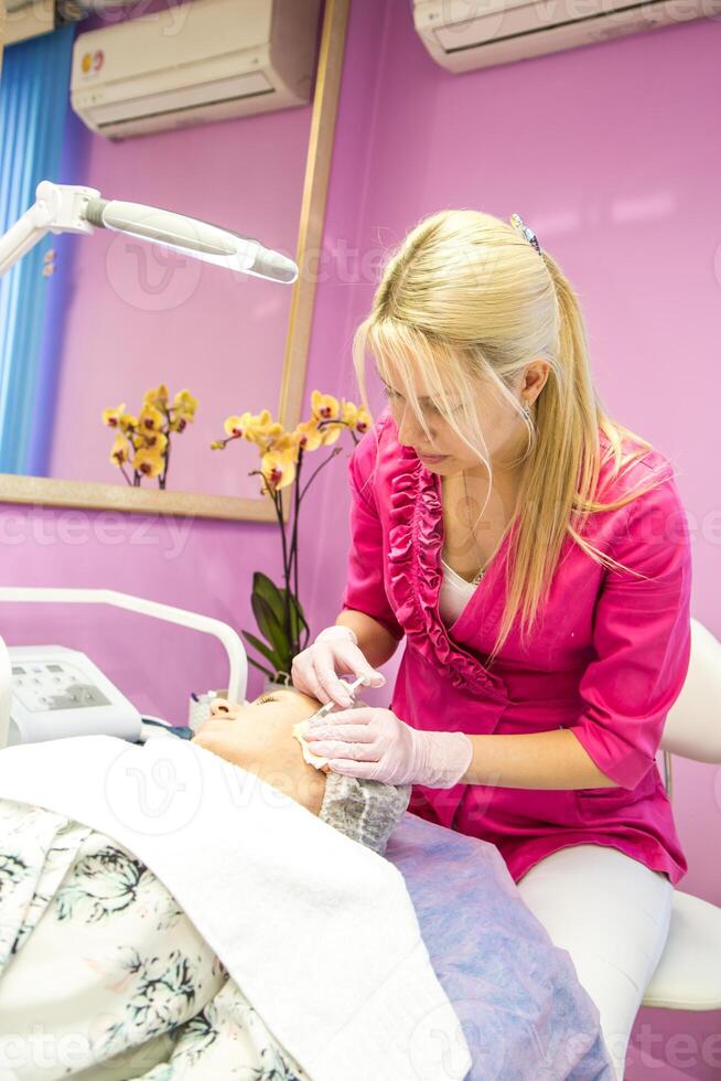 This image shows a cosmetic procedure in progress with administering an injection to a client's face photo
