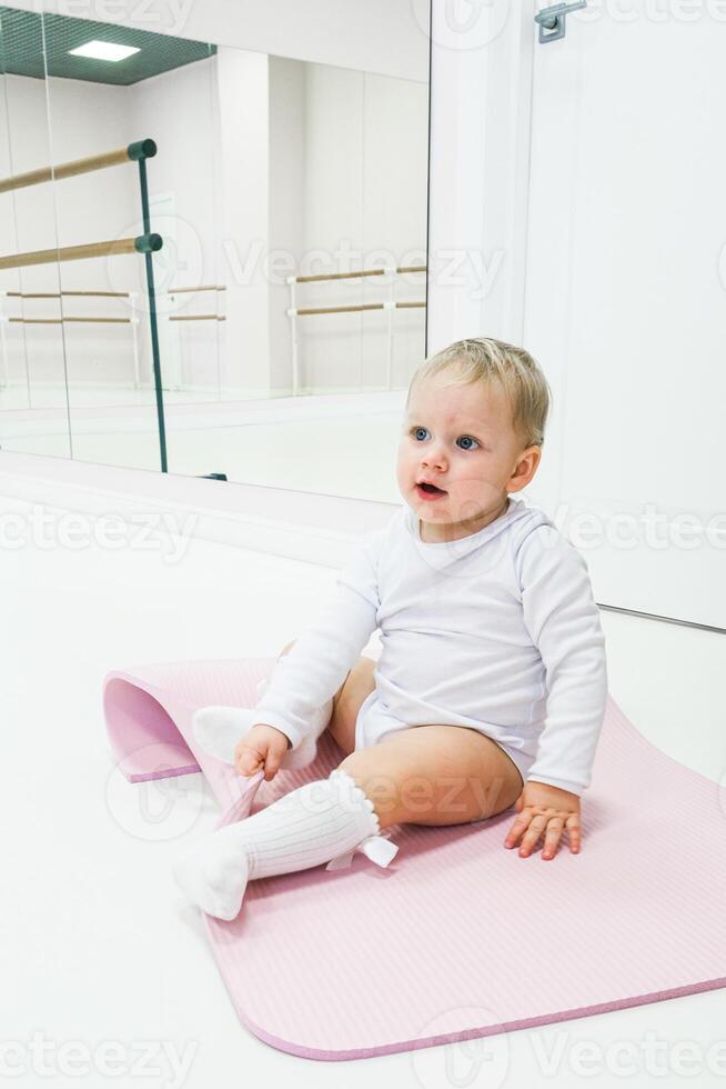 A baby sitting on a pink mat in a room photo