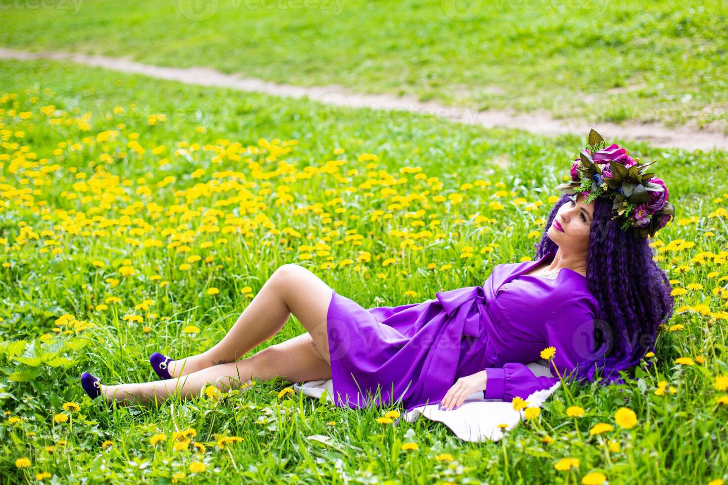 A woman in purple dress laying on the grass photo