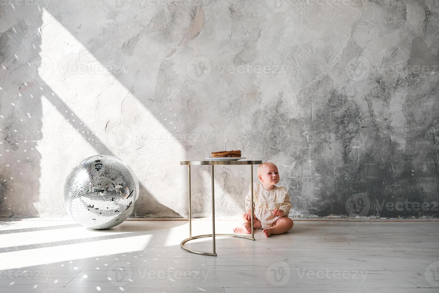 A baby sitting on a table in front of a wall photo