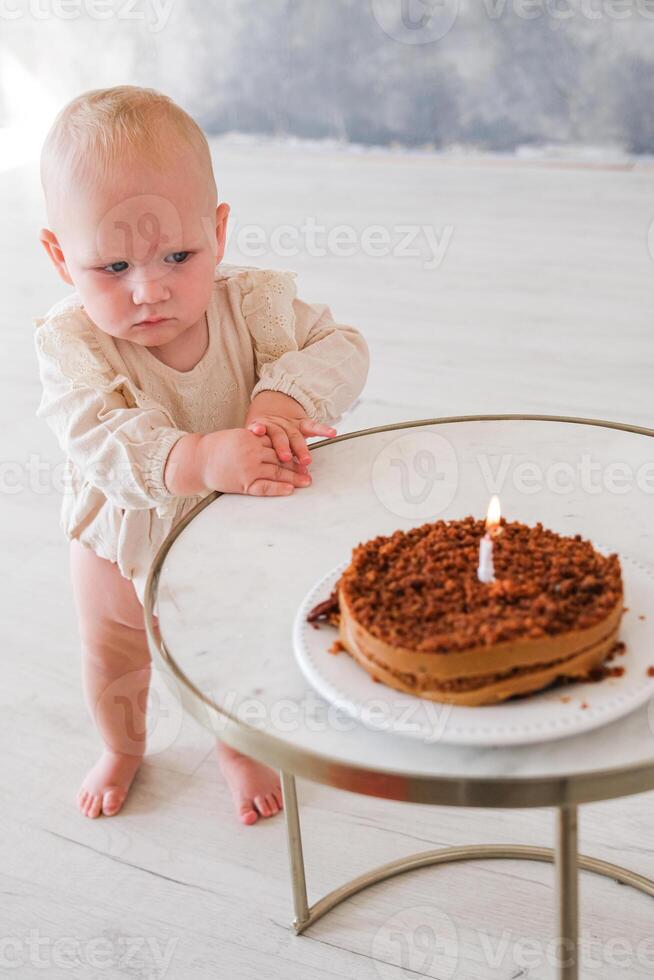 A baby sitting on a table with a cake photo