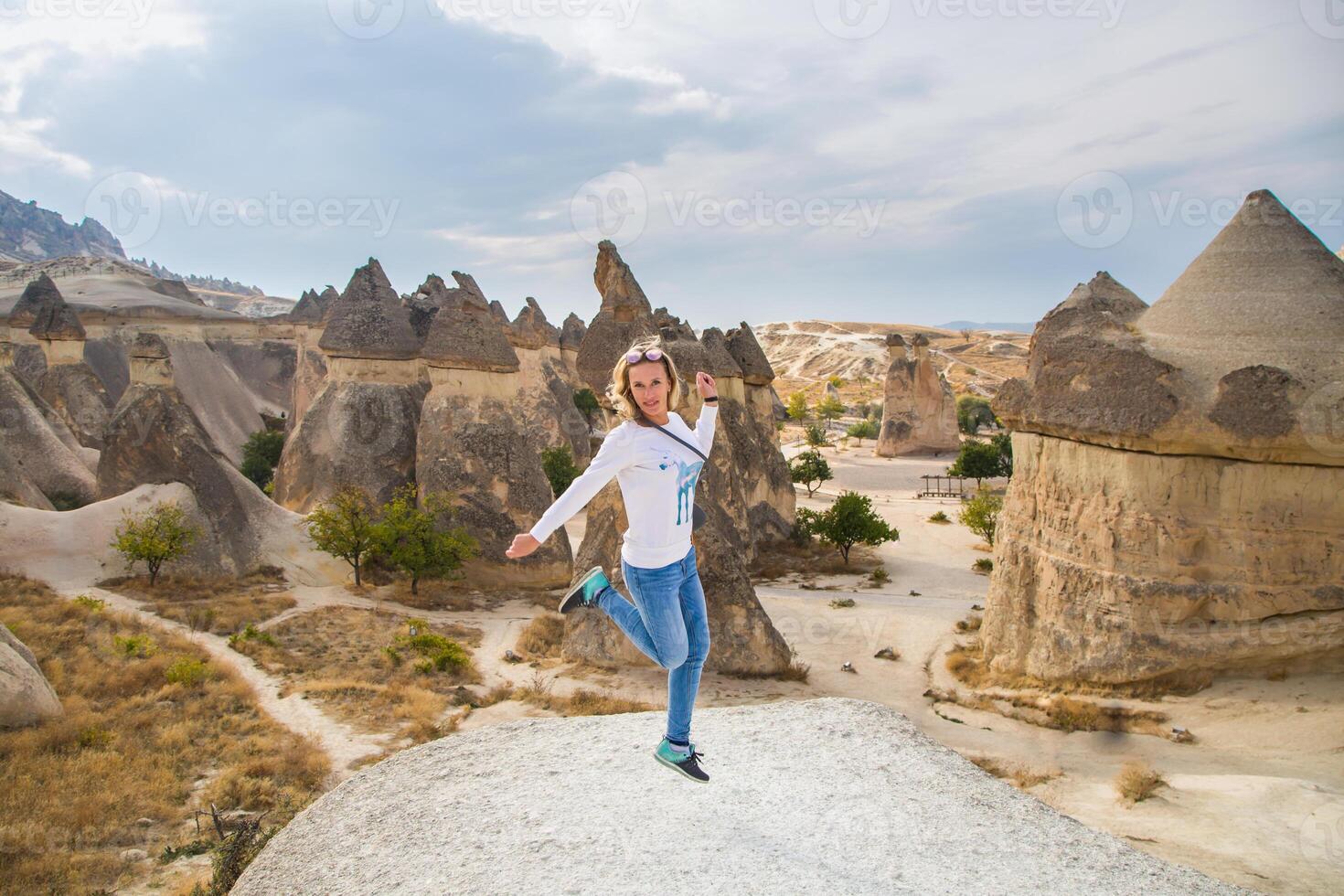 A woman jumping on a rock in front of some rock formations photo