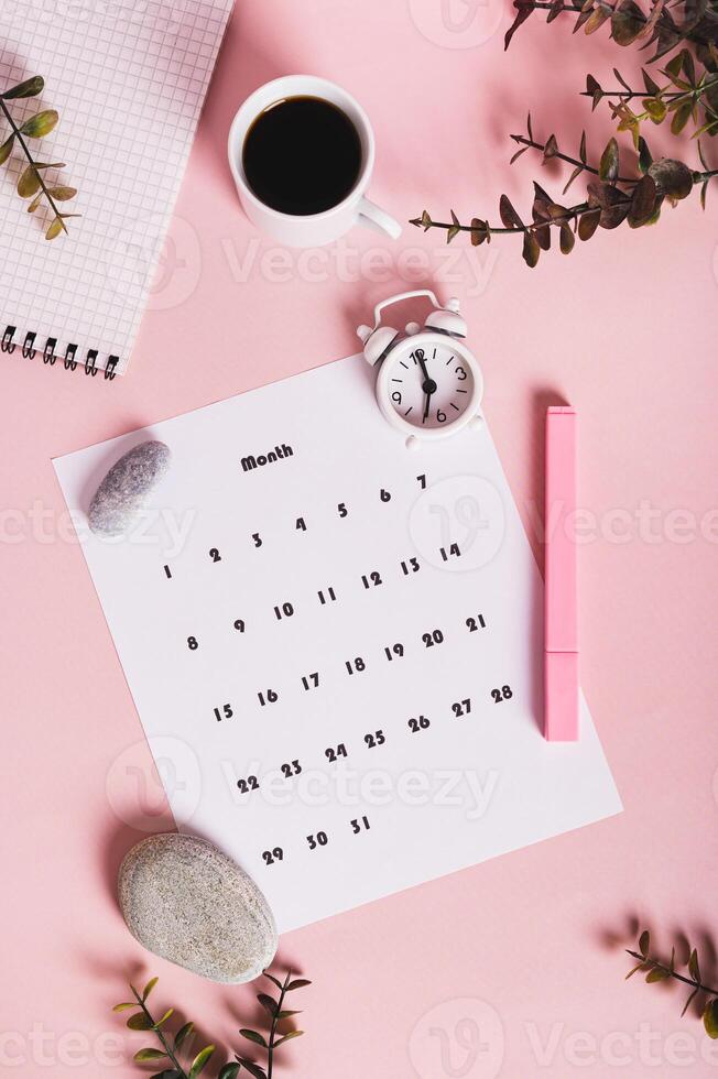 Calendar, alarm clock, notebook and pen on a pink background top and vertical view photo