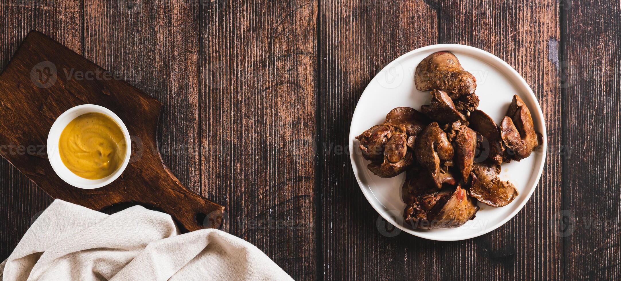 Homemade stewed chicken liver on a plate on the table top view web banner photo